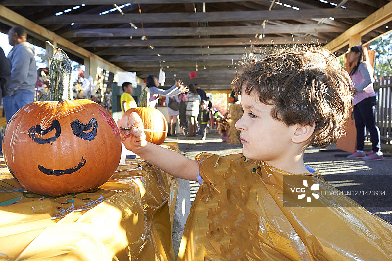 小男孩在丰收节上画南瓜图片素材