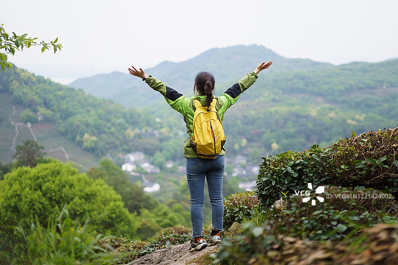 在山顶张开双臂的亚洲女性图片素材