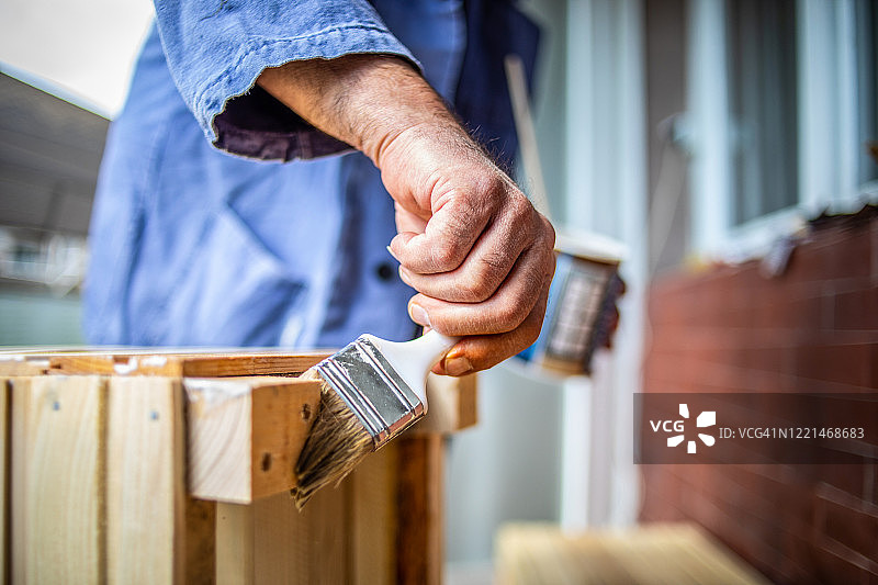 一位年长的男人在木质表面上涂油漆图片素材
