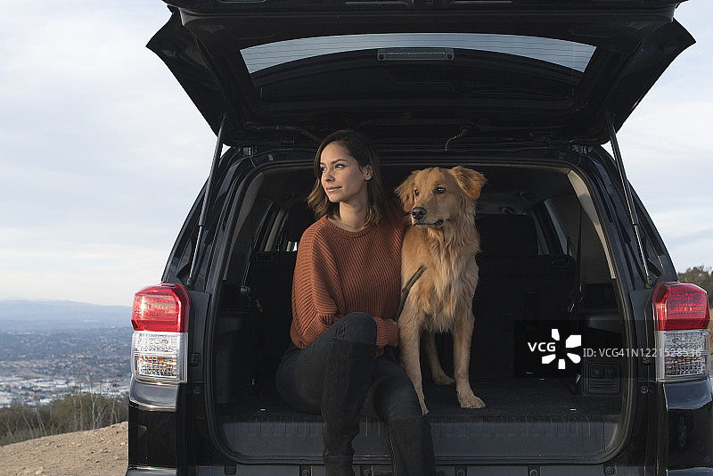 年轻女子和她的金毛猎犬坐在车后座图片素材