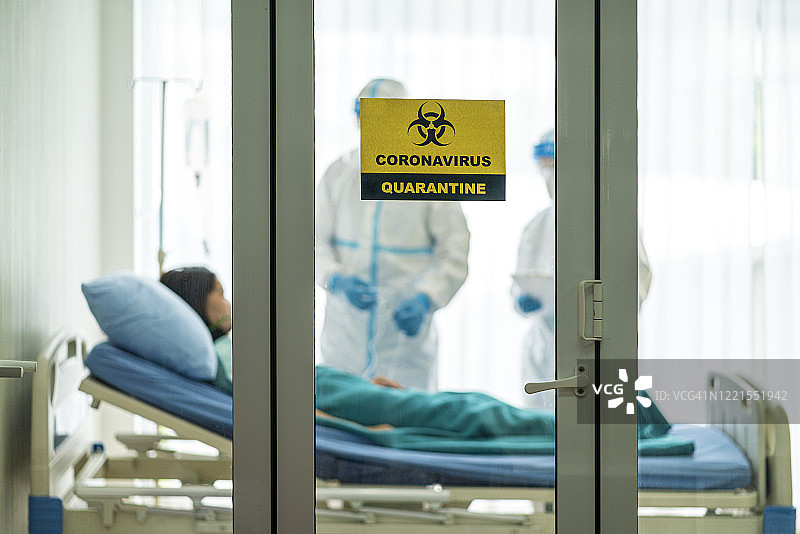 穿戴PPE防护服的亚洲医生在隔离病房内使用呼吸机为新型冠状病毒患者治疗图片素材