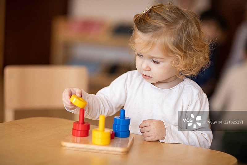 可爱女孩在日托游戏室玩益智玩具图片素材