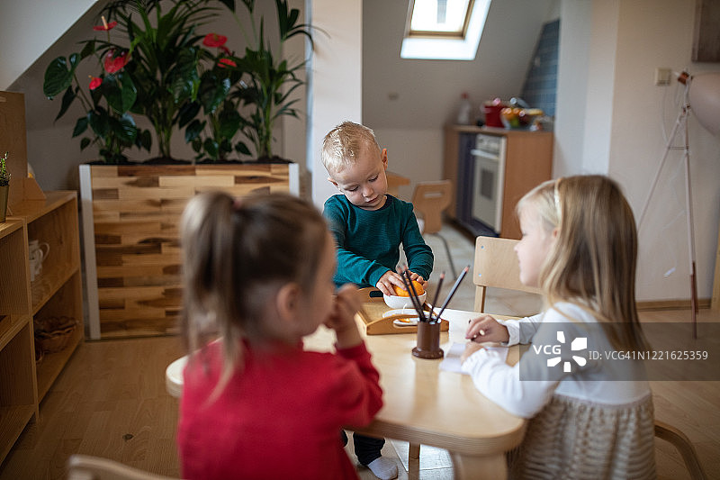 在日托教室里剥橘子的小男孩图片素材