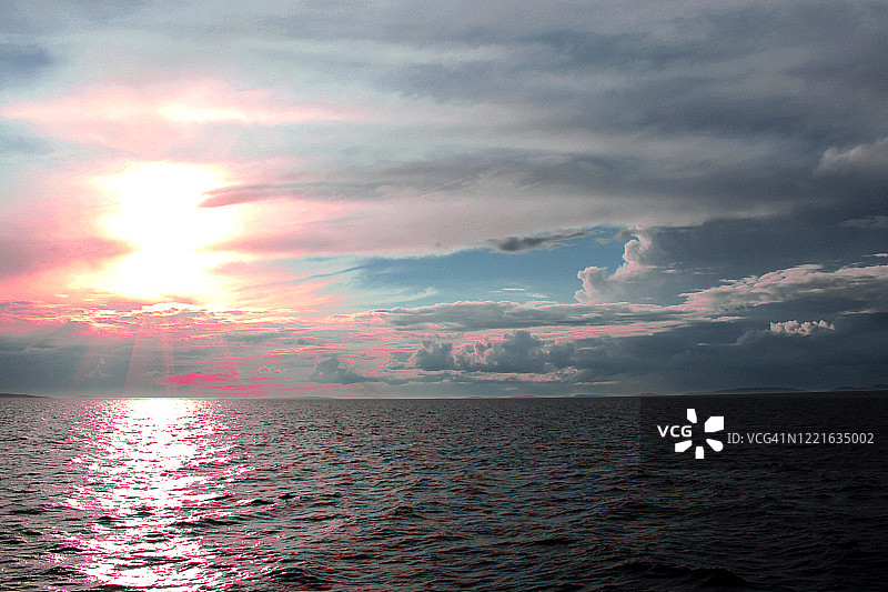 黄昏时分白海的日落，壮丽的天空，阳光穿透云层，水面倒影图片素材