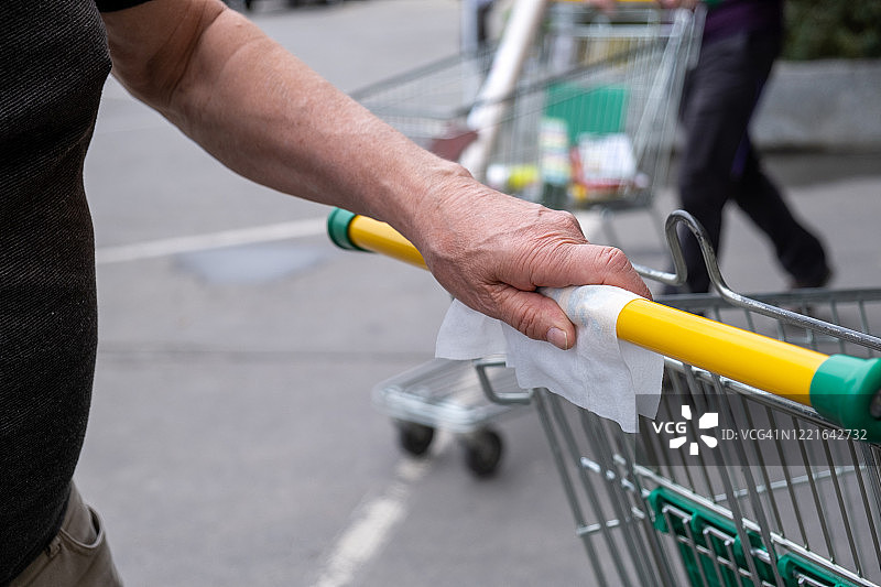 老年男人近距离消毒购物车把手图片素材
