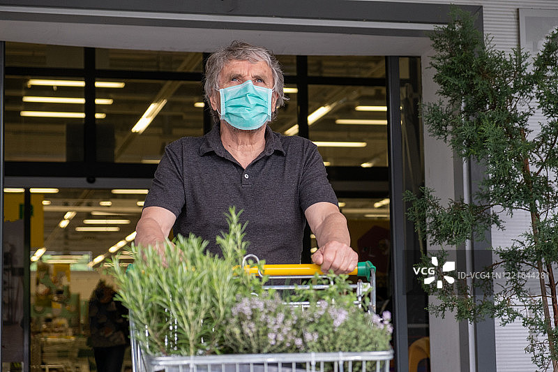 戴口罩的老人推着购物车购物图片素材
