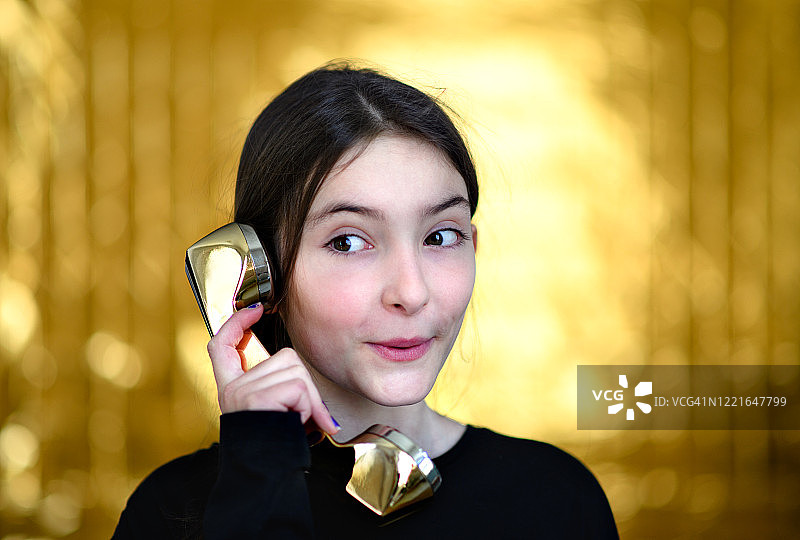 在家玩金色电话听筒的小女孩肖像图片素材
