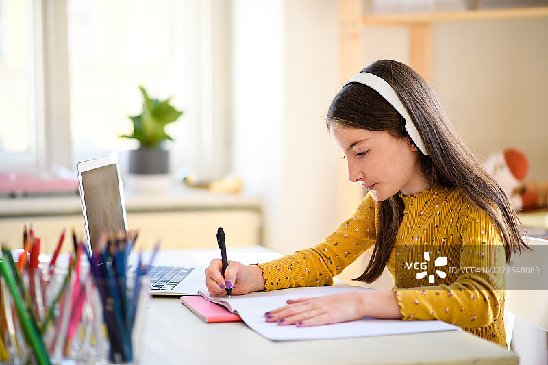 在家学习的女孩，戴着耳机用笔记本电脑图片素材