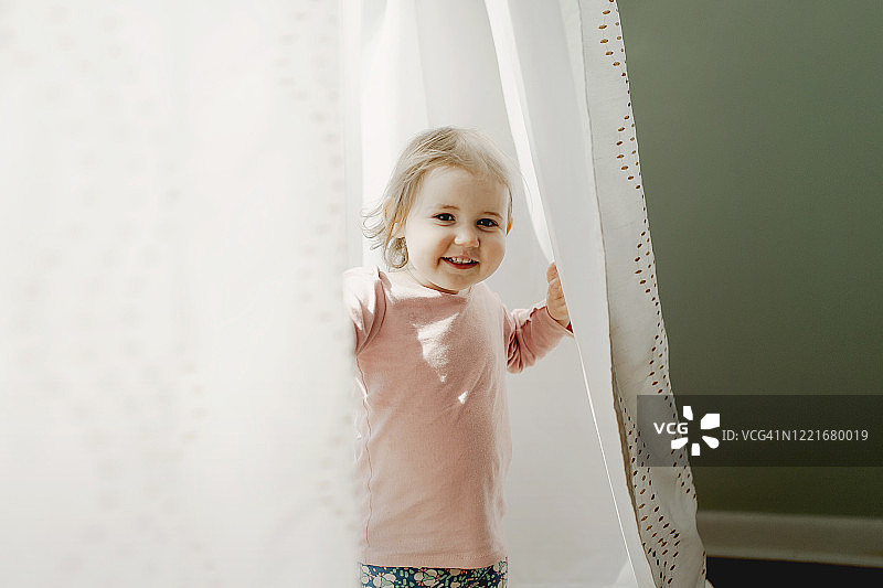在窗帘里玩捉迷藏的女童图片素材
