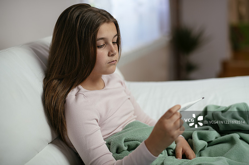 床上拿着体温计的生病小女孩照片图片素材