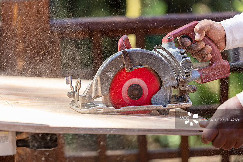 男人用电动圆锯锯木头图片素材