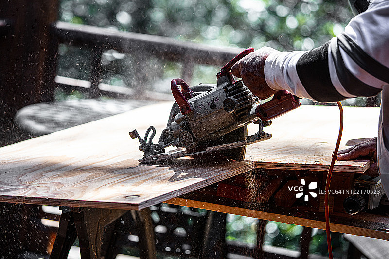 男子在户外用电锯锯木头图片素材