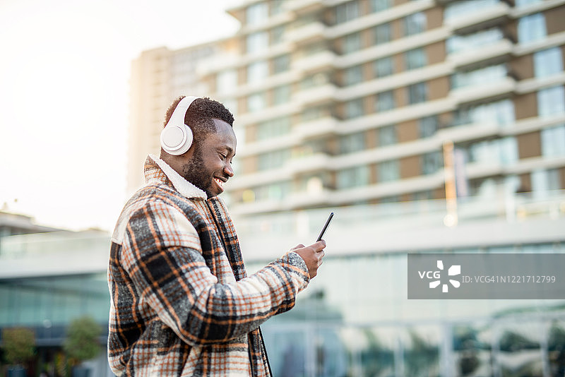 快乐的年轻男人在手机上阅读文章。图片素材