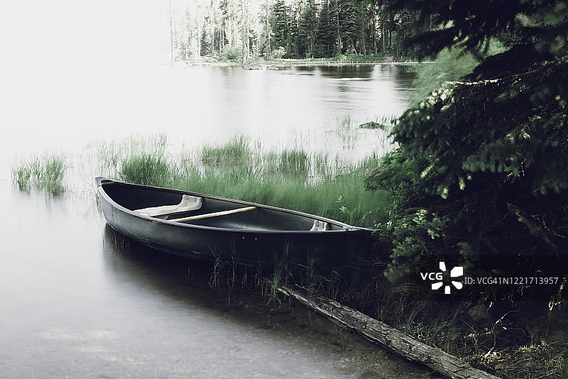 在爱达荷州麦考尔上佩耶特湖岸边，长时间曝光下的超平静水面和一叶深绿色独木舟图片素材