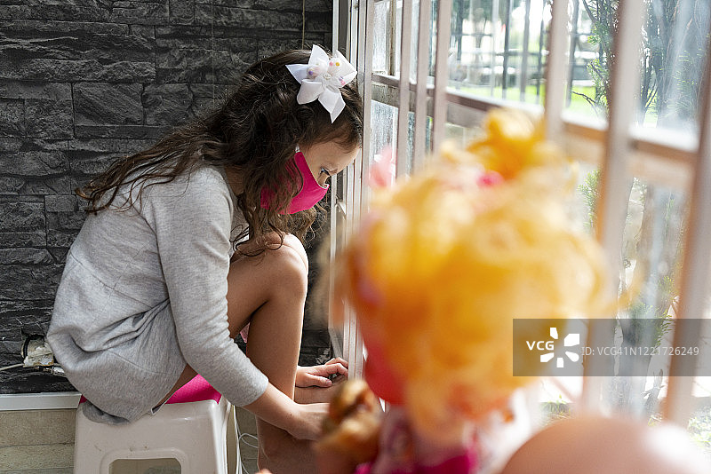 坐在窗边长椅上看着地面的5岁女孩图片素材