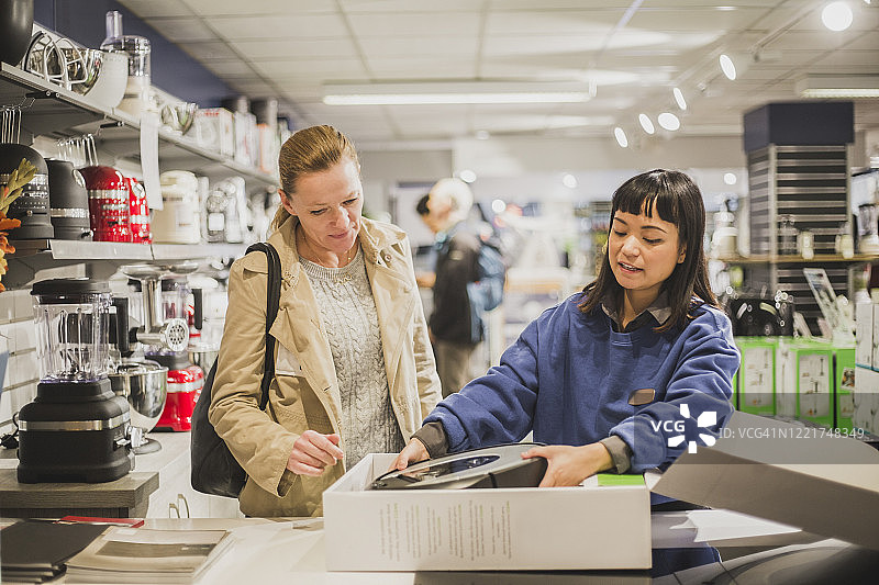 女销售员在店内为顾客开箱电器图片素材
