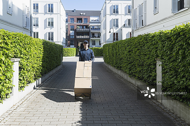 年轻快递员用手推车运送包裹图片素材