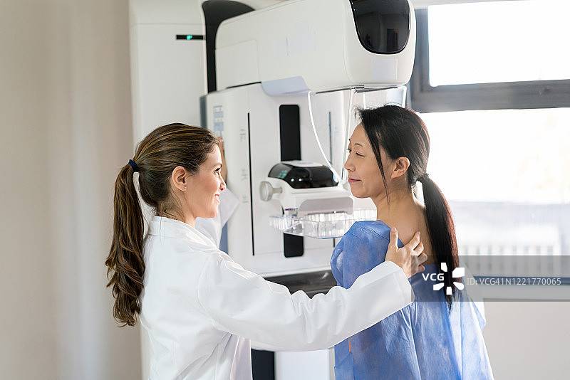 与病人交谈并调整位置进行乳房X光检查的女医生图片素材