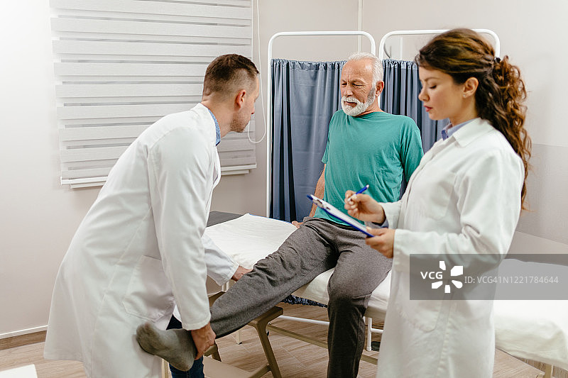 医生检查老年男性患者的腿部损伤图片素材