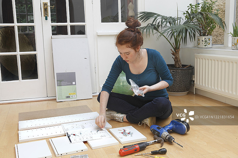 年轻女孩组装“平板包装”DIY柜子图片素材