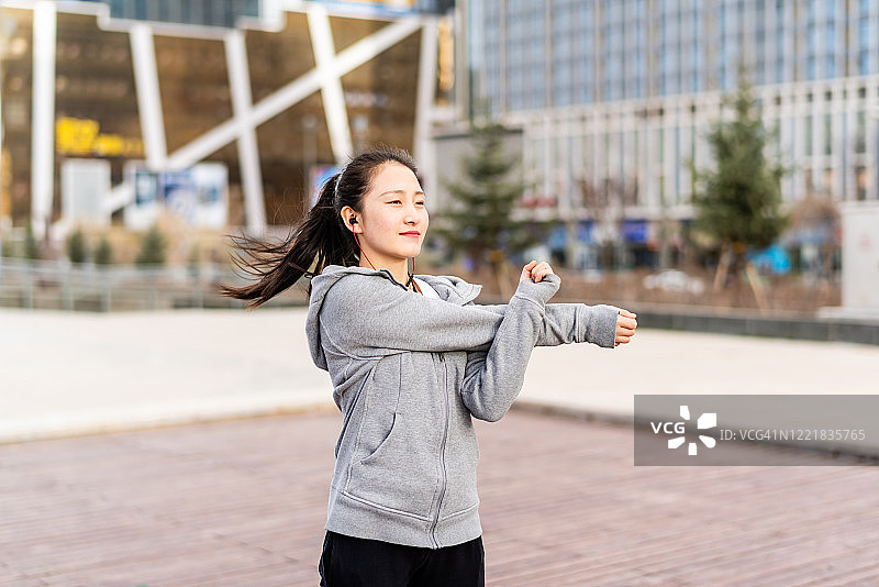 戴着耳机在城市街道上锻炼的亚洲成年学生图片素材