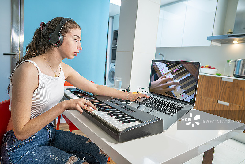 音乐视频会议：少女在家中厨房远程教钢琴老师图片素材