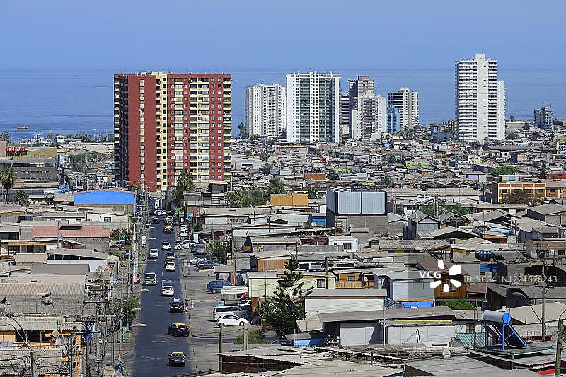 智利塔拉帕卡大区伊基克市，摩天大楼前的典型简易住宅楼图片素材
