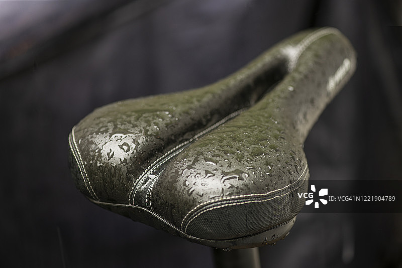 深色背景下的湿自行车座特写图片素材