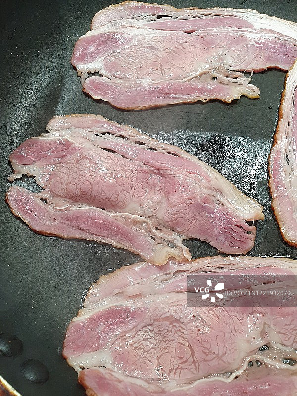 不粘锅中的牛肉片和培根特写图片素材