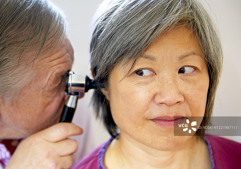 听力医师用耳镜检查中年妇女的耳朵图片素材
