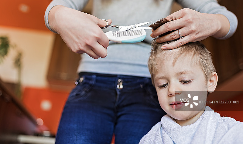 隔离期间，母亲为可爱的儿子理发图片素材