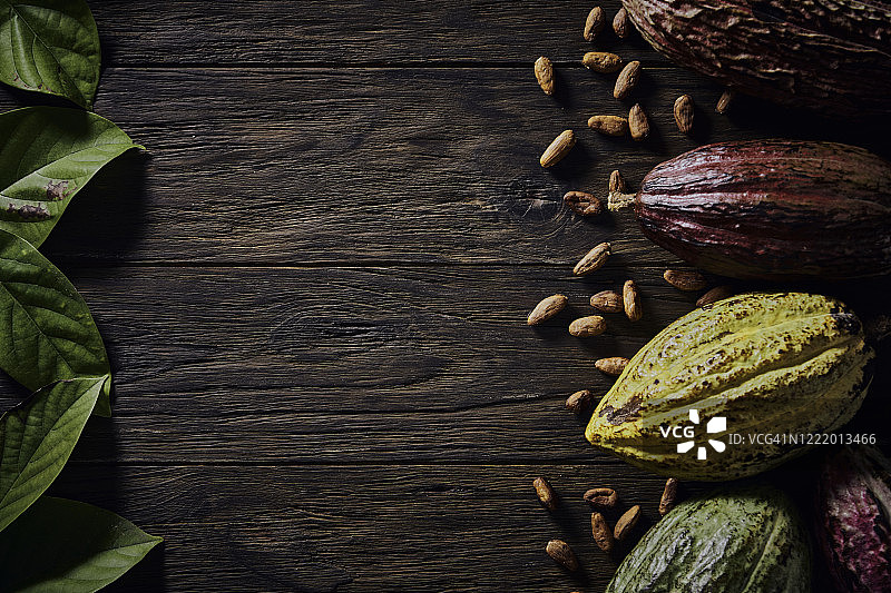 旧式风格的可可豆和可可果实低调图片，位于木制乡村桌子上，框架内有复制空间图片素材