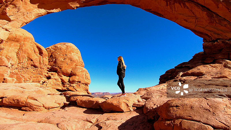 金发女孩在拱门国家公园的南窗拱门前惊叹不已图片素材