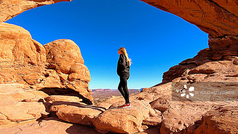 金发女孩在拱门国家公园的南窗拱门前惊叹不已图片素材