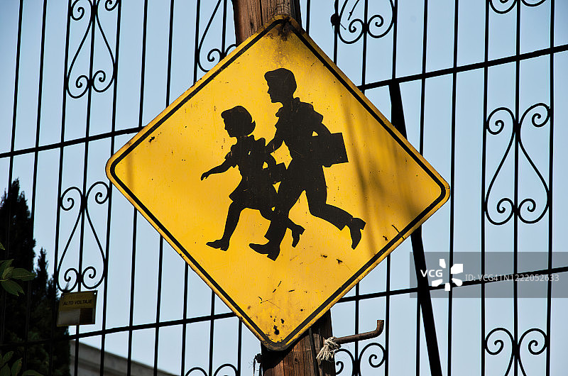 小学生在交通警告标志前过马路图片素材