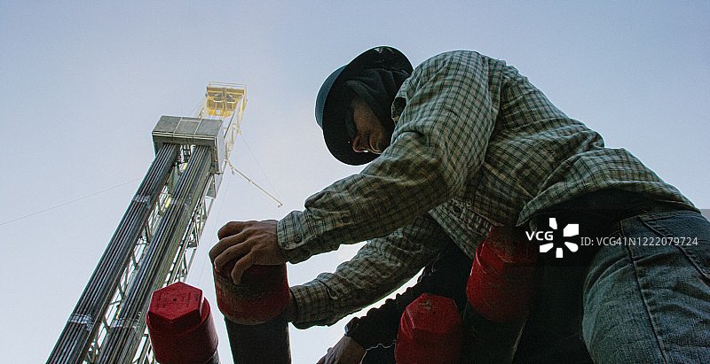 钻井平台油田工人拧紧保护帽。图片素材