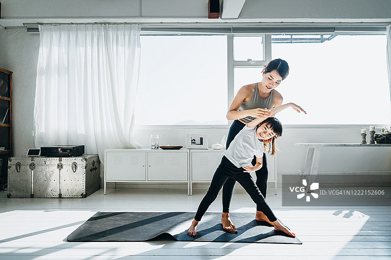 快乐的亚洲年轻母亲和女儿在家一起做瑜伽图片素材