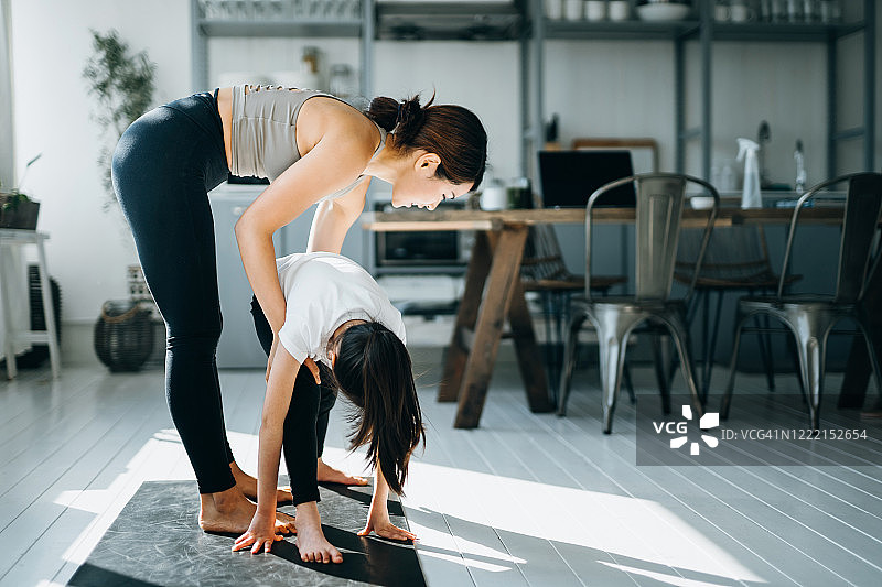 快乐的亚洲年轻母亲和女儿在家一起做瑜伽图片素材