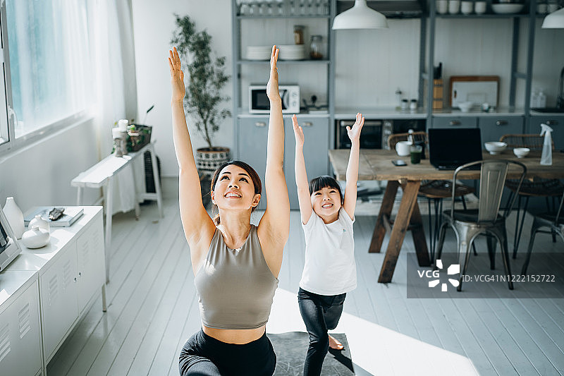 快乐的亚洲年轻母亲和女儿在家一起做瑜伽图片素材