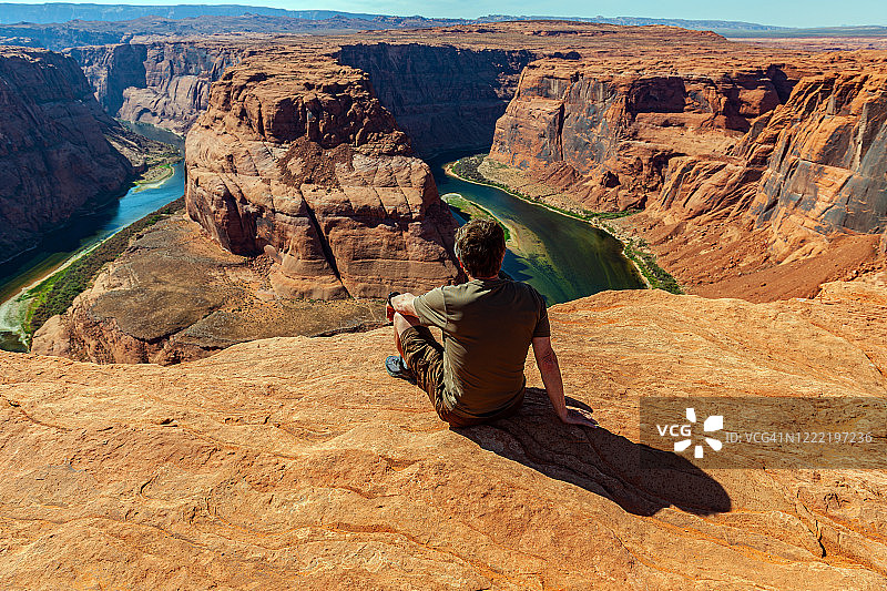 男人欣赏美国亚利桑那州科罗拉多大峡谷马蹄湾的美景图片素材