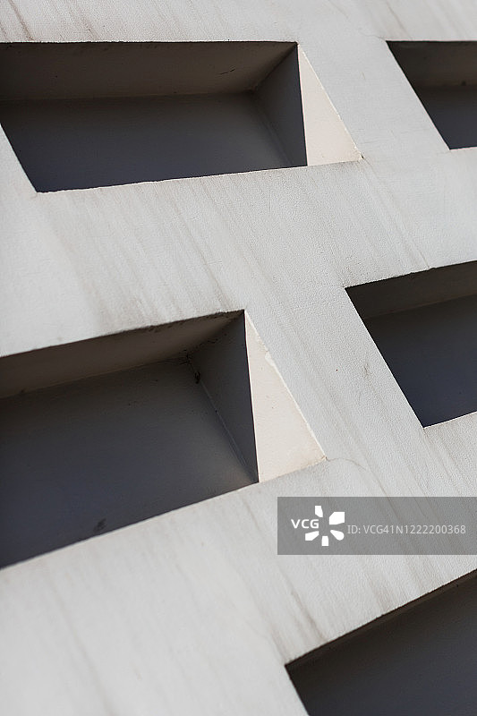 阳光照耀着带有几何形状孔洞的混凝土墙图片素材