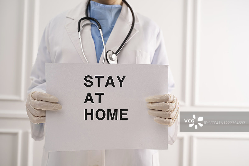 医生拿着写有“居家隔离”字样的纸图片素材