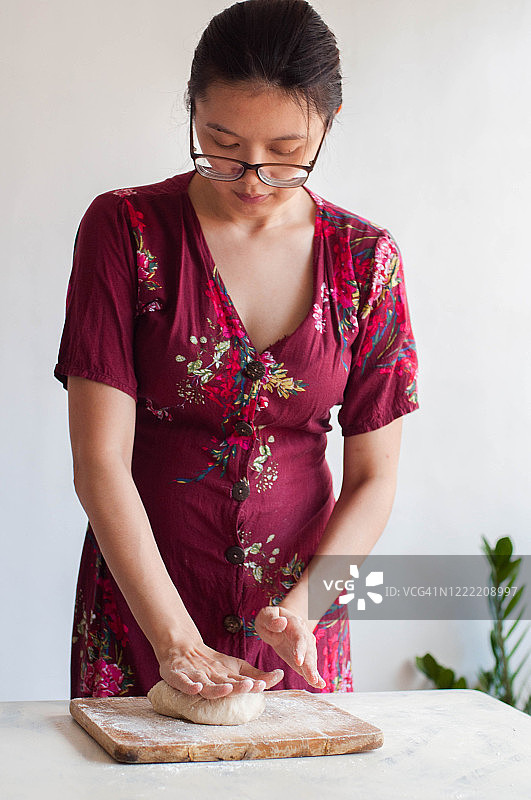 年轻的东南亚女人在家揉面团图片素材