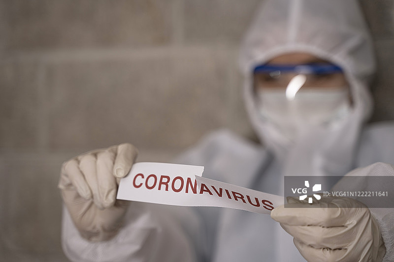 身穿防护服的医生撕毁带有冠状病毒文本的纸张图片素材
