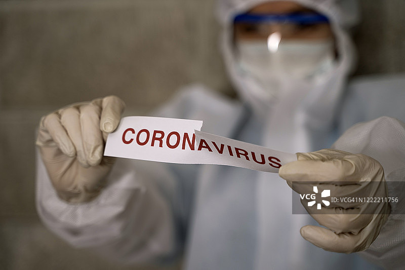 身穿防护服的医生撕毁带有冠状病毒文本的纸张图片素材