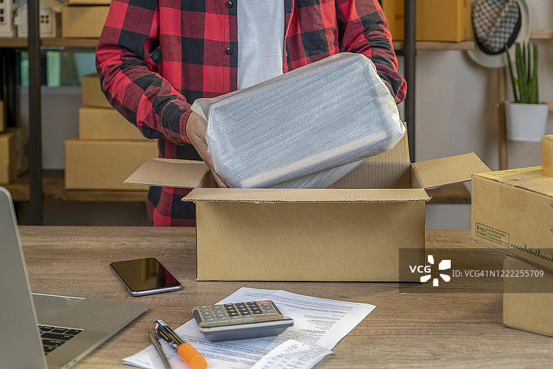 男子在仓库用胶带打包包裹特写图片素材