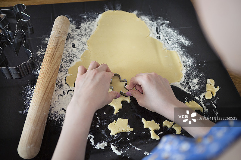 青少年肩后视角，撒粉厨房台面用模具切面团。图片素材