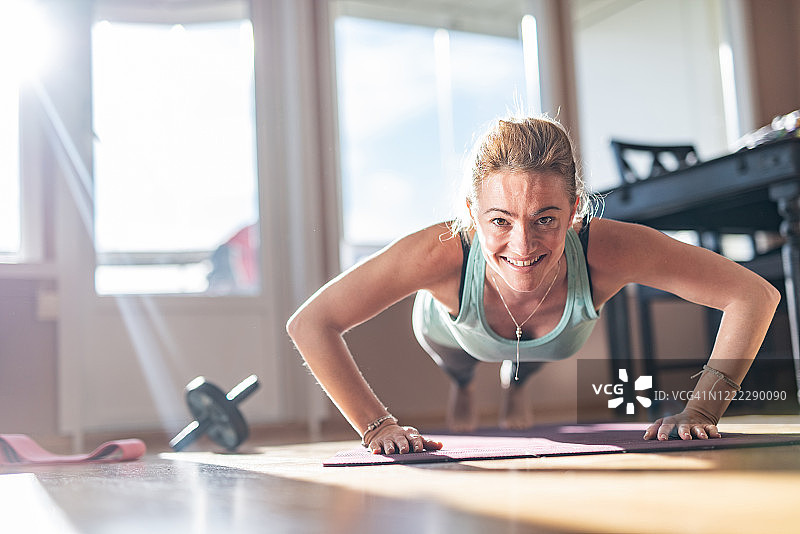 在阳光明媚的室内做俯卧撑的健壮女人图片素材