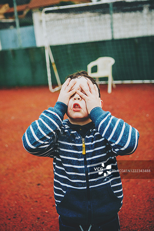 用手捂住眼睛的男孩，悲伤图片素材