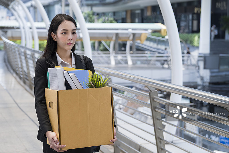 被解雇的女人抱着她的物品离开办公室图片素材